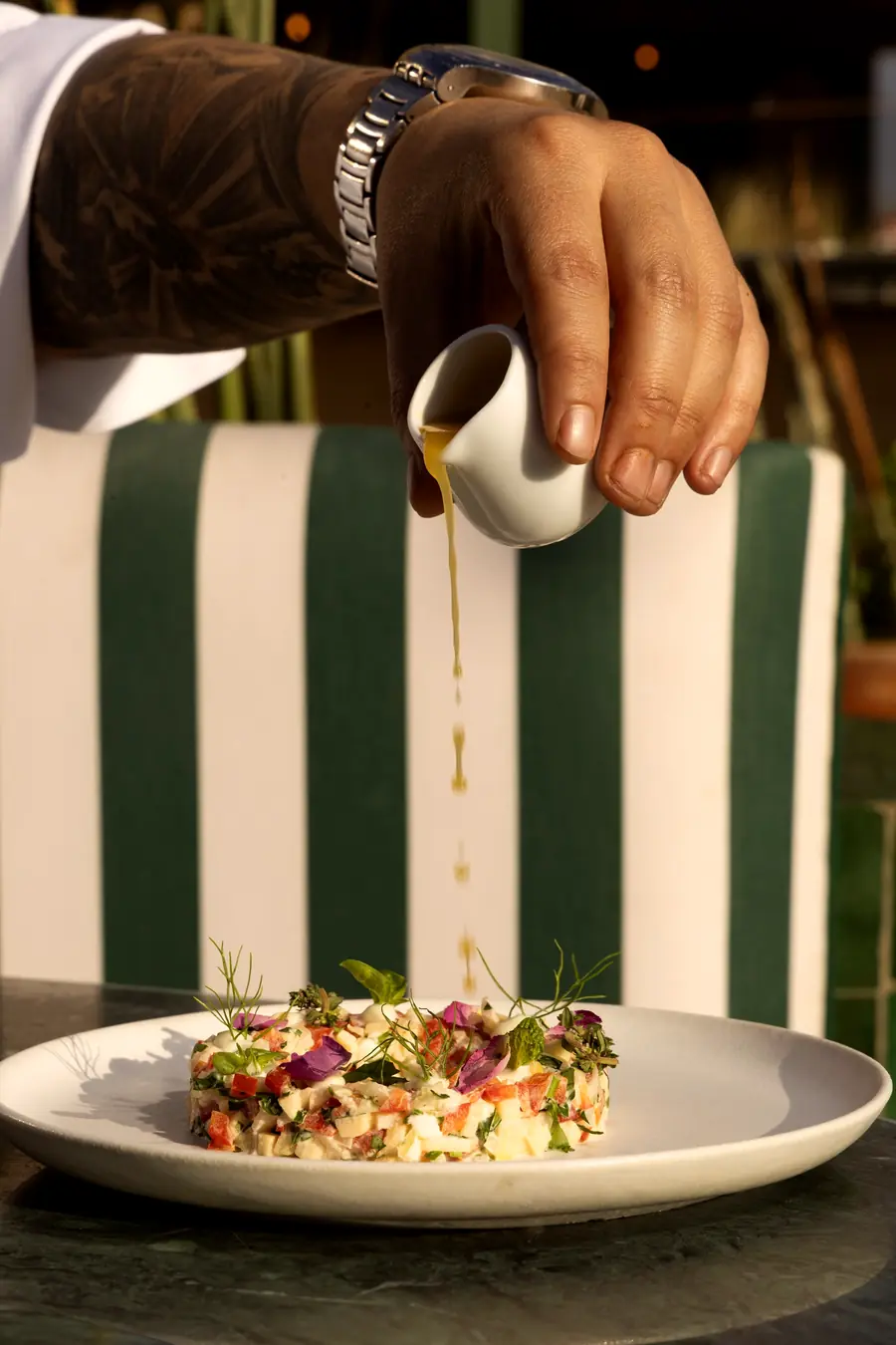 Sauce versée à table sur une assiette fraîche, banquette rayée verte et blanche